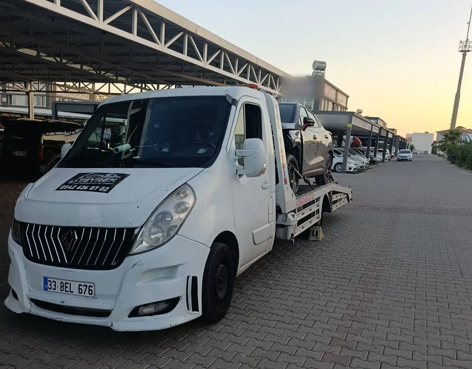 Aksu’ya hizmet veren Zeyrek Oto Çekici akşam saatlerinde koyu renkli bir otomobili platformlu çekiciyle taşıyor