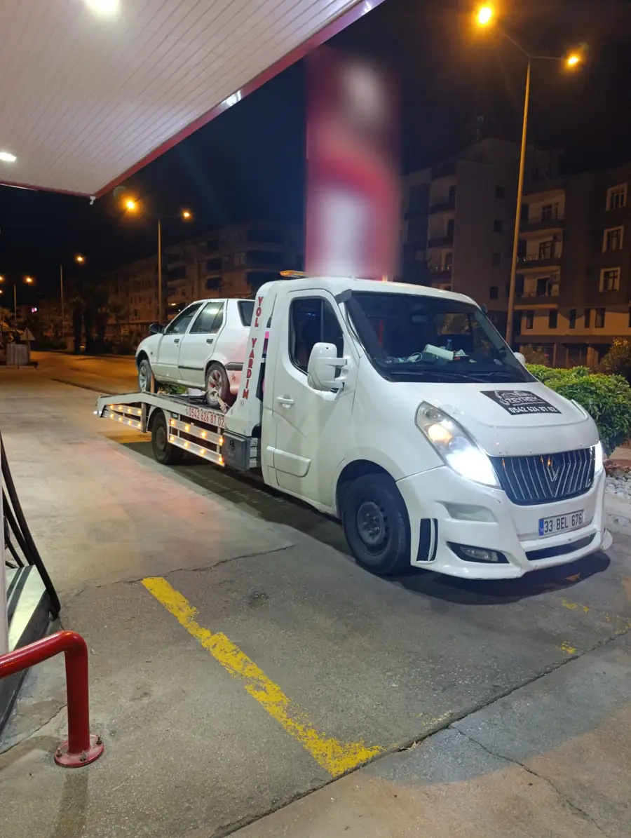 Akaryakıt istasyonunda gece, platformlu oto çekici beyaz bir otomobili kayar platforma almış