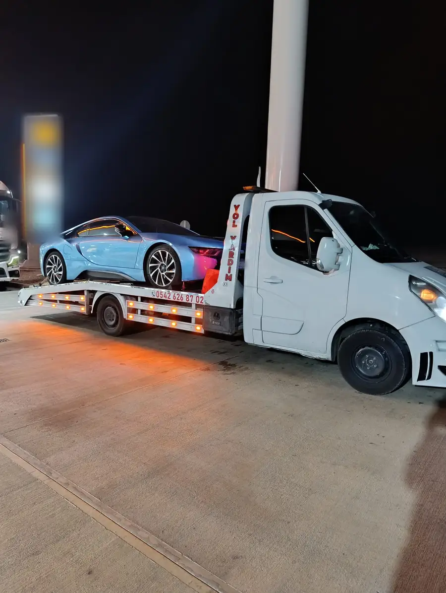 Mavi bir spor otomobil, gece platformlu oto çekicinin kayar platformunda taşınıyor