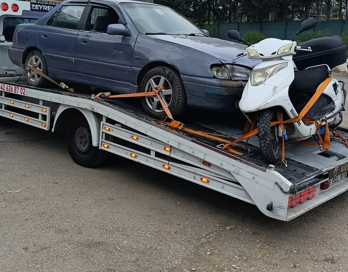 Zeyrek Oto Çekici’nin kayar platformunda kayışlarla sabitlenmiş beyaz bir scooter motosiklet, yanında bir otomobil