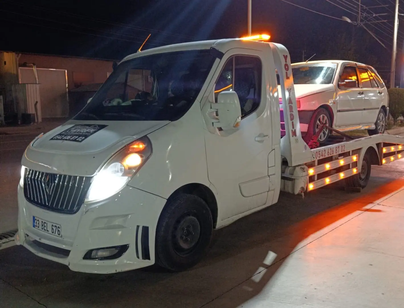 Antalya’da gece, sarı uyarı lambaları yanan Zeyrek Oto Çekici kayar platformunda beyaz bir otomobil taşıyor