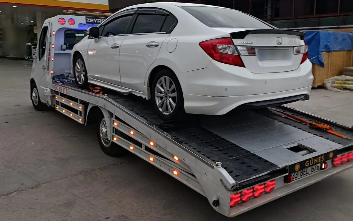 Şehirler arası araç taşımada Zeyrek Oto Çekici’nin kayar platformlu çekicisi beyaz bir sedan otomobili taşıyor