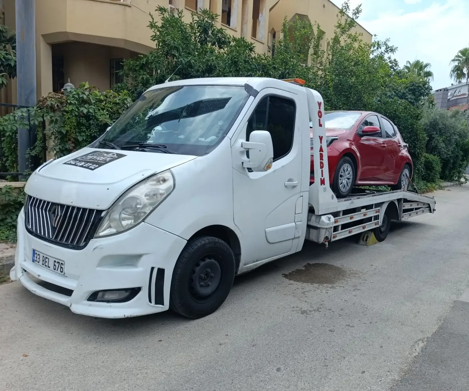 Zeyrek Oto Çekici’nin kayar platformlu çekicisi Antalya’da kırmızı bir otomobili platformuna almış